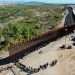 Inmigrantes esperan para ser procesados por la Patrulla Fronteriza en la barrera entre EE. UU. y México en Yuma, Arizona. Foto: CBS.