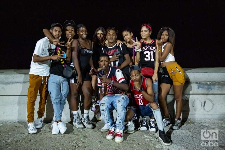 Grupo de adolescentes con camisetas de básquet en el muro del malecón de La Habana de noche Foto Jorge Ricardo.