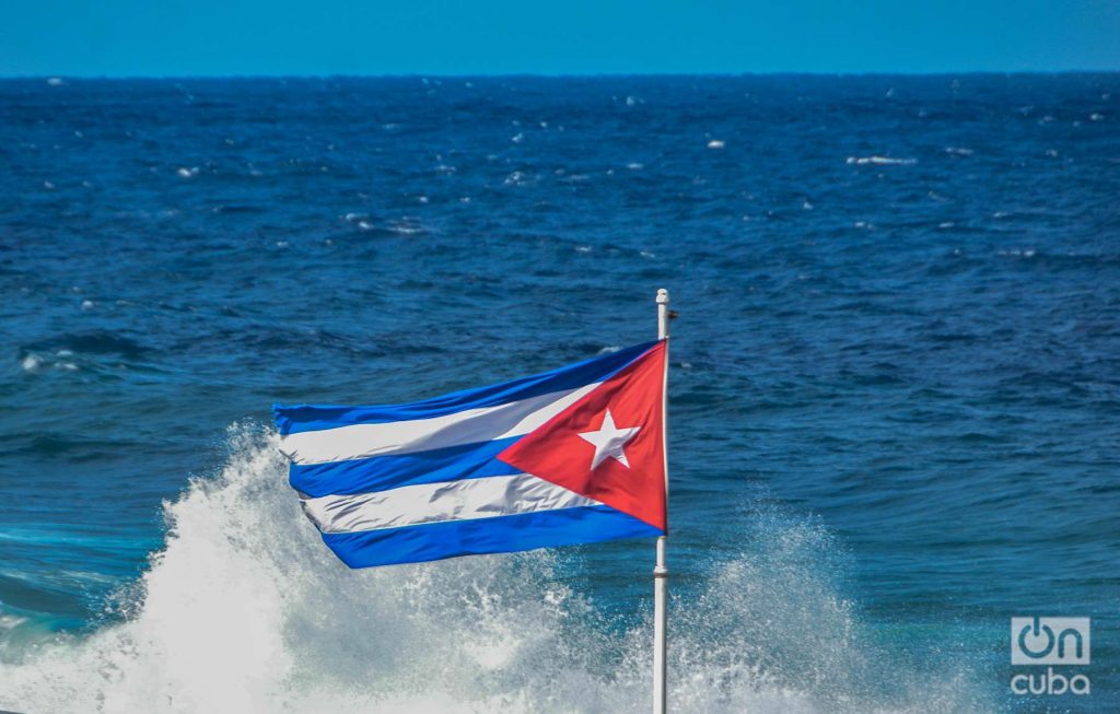 Cuban flag in the waves of the sea on the Malecón in Havana photo: Kaloian
