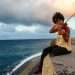 Mujer toca violín sentada en el muro del malecón de La Habana con el mar de fondo Cuba 2022 Foto: Jorge Ricardo
