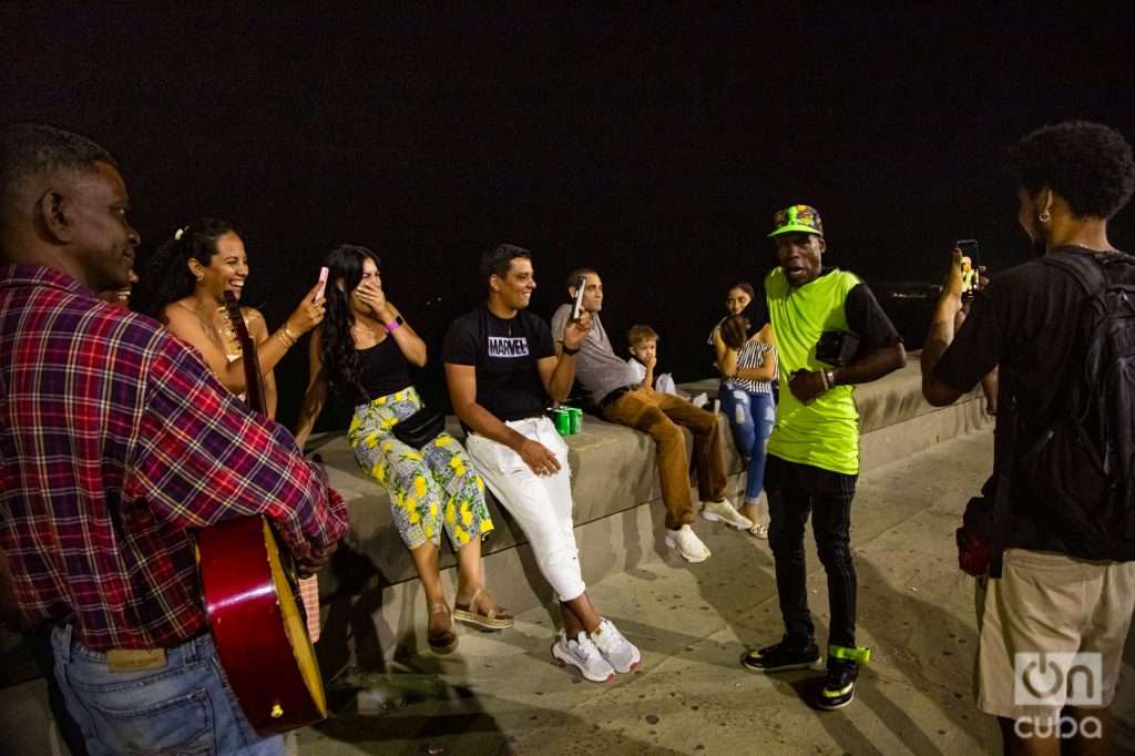 Grupo de personas en torno a un hombre que rapea de noche en el malecón de La Habana, Cuba. Foto: Jorge Ricardo