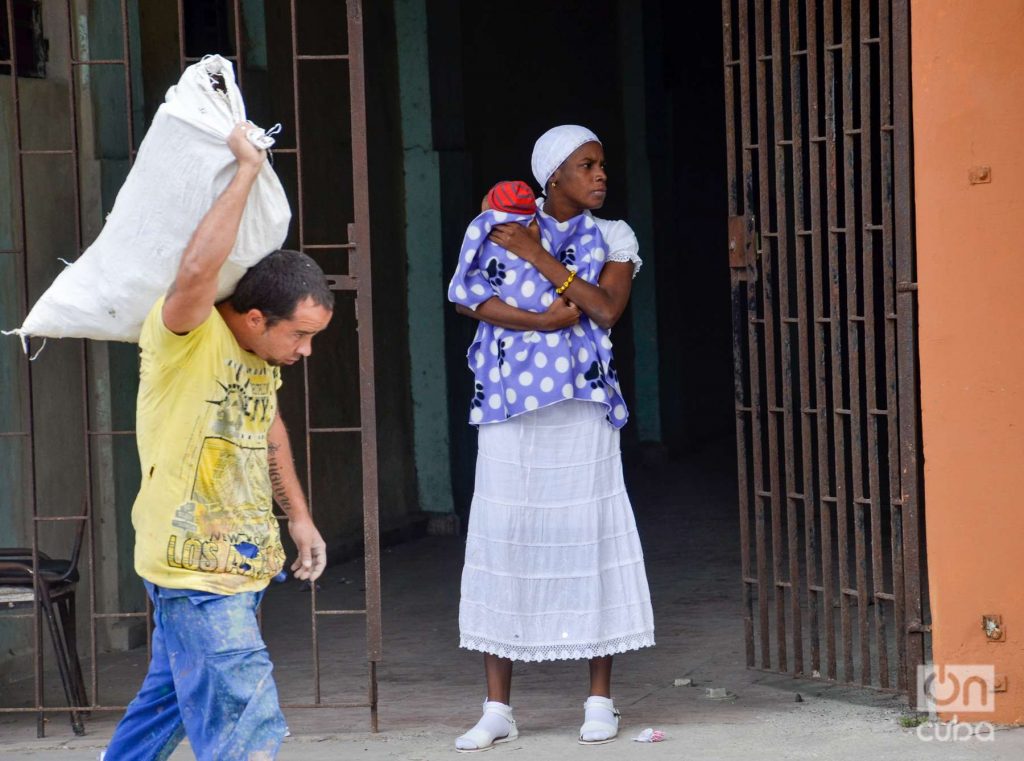 Man carries sack woman with baby in arms. Photo: Kaloian