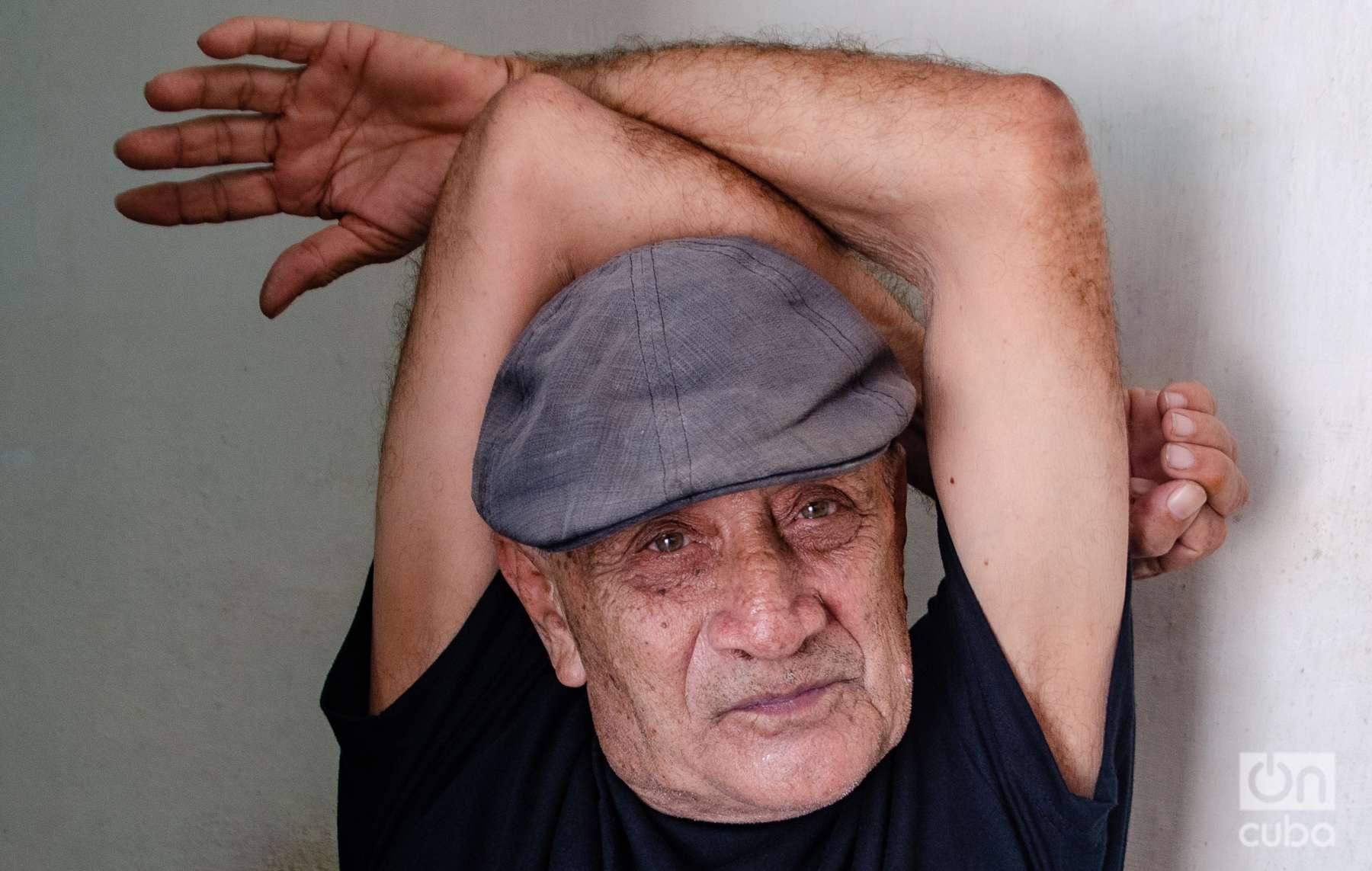 el poeta cubano Delfín Prats con los brazos cruzados en alto. Holguín, Kaloian.