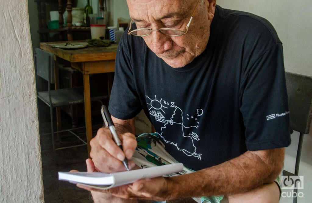 Delfín Prats writes with his “América Invertida” pullover.  Photo: Kaloian.