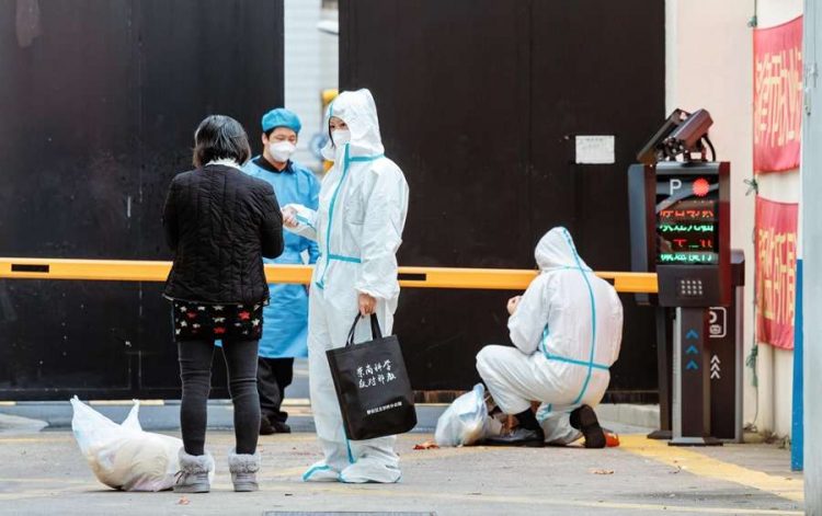 Trabajadores de la salud dirigen a personas que dieron positivo por coronavirus al área de cuarentena, en Shanghái, China. Foto: EFE.