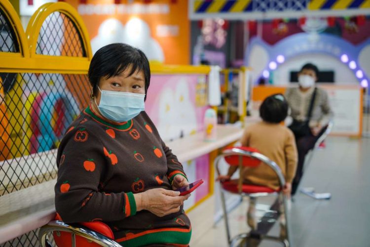 Una mujer protegida con una mascarilla utiliza su móvil en un centro comercial de Pekín este 11 de enero de 2023. Foto; Wu Hao / EFE.