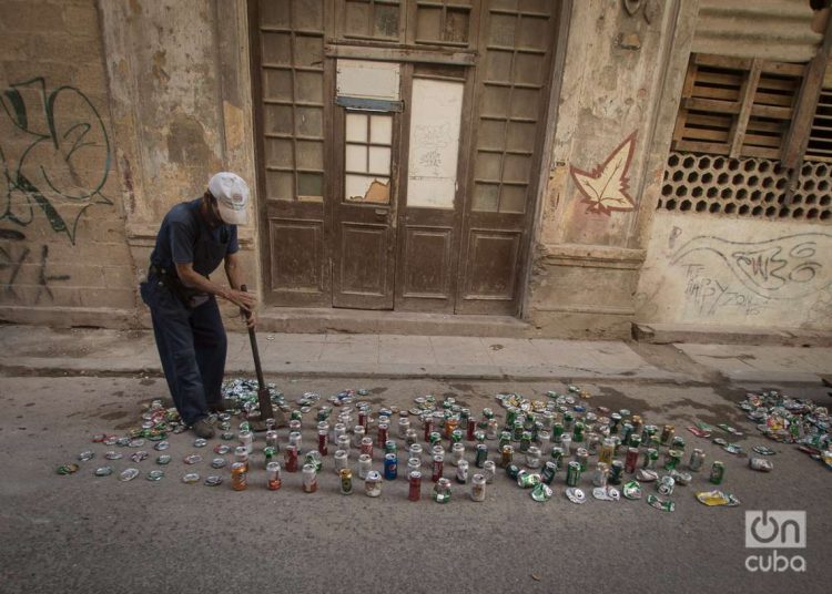 Un hombre aplasta latas de refresco para luego vender como materia prima. Foto: Otmaro Rodríguez.