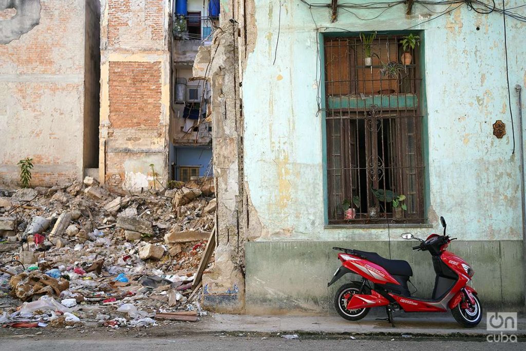 Ruinas de un edificio junto a un vehículo eléctrico en fachada de La Habana, Cuba, 2023. Foto: Alejandro Ernesto.