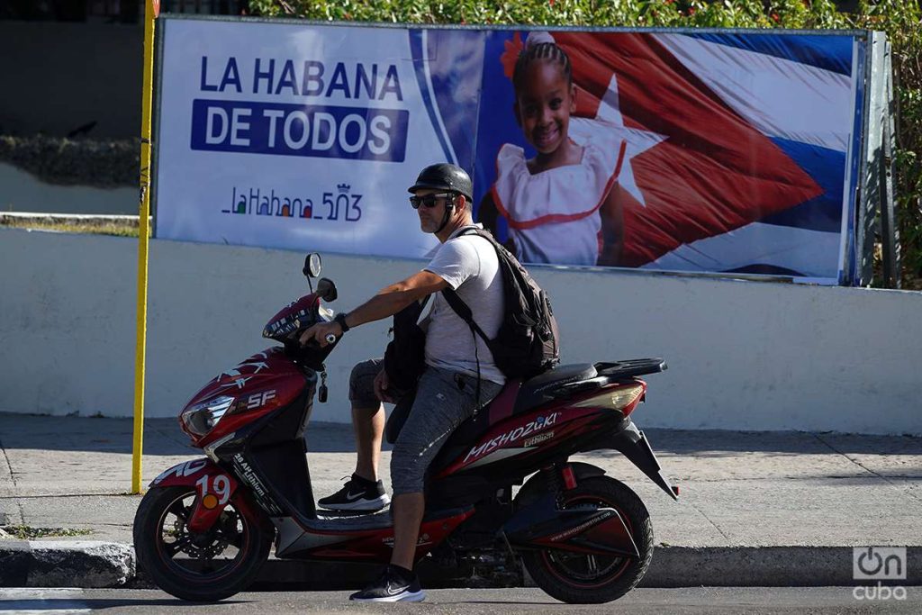 Hombre en moto eléctica con cartel de La Habana al fondo en Cuba, 2023. Foto: Alejandro Ernesto.
