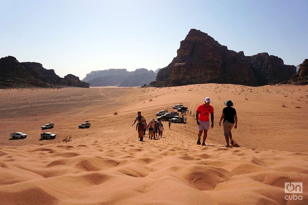 Sun-baked tourists climb a sandy promontory in Wadi Rum.  Photo: Alejandro Ernesto.