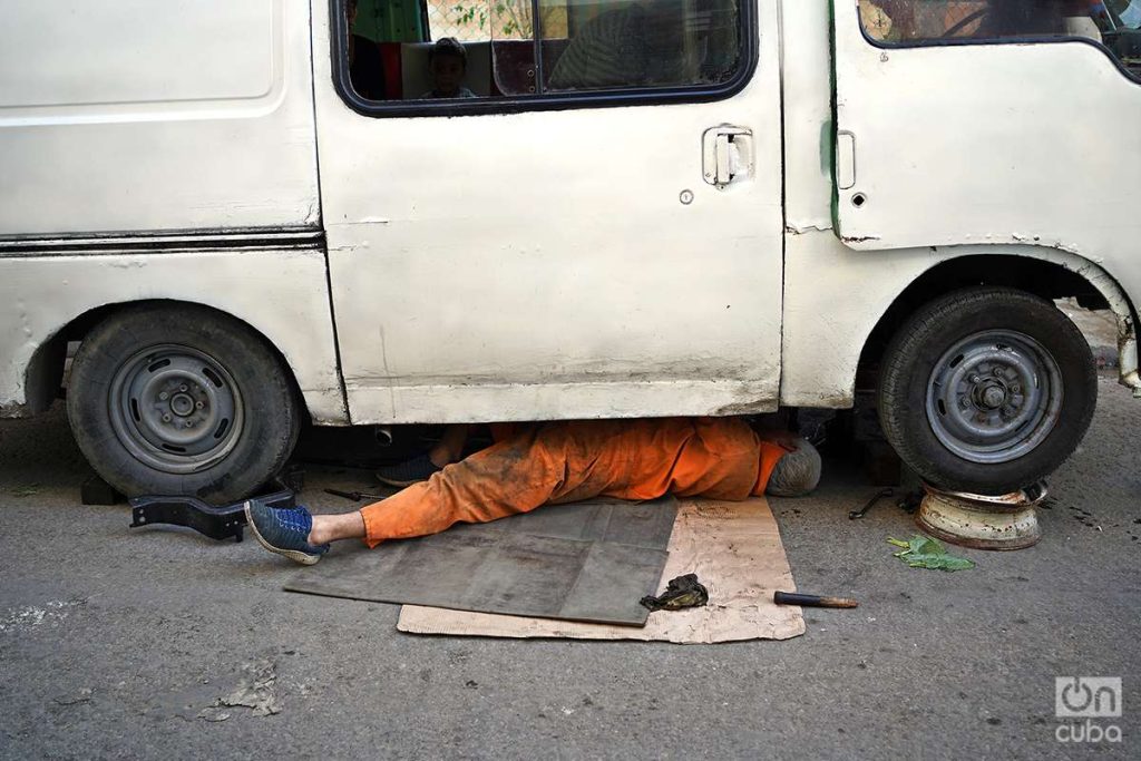 Mecánico debajo de un auto en La Habana 2023. Foto: Alejandro Ernesto.