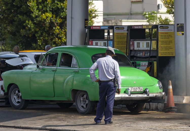 Un policía (de espaldas) observa a un coche antiguo en una gasolinera, en La Habana. Foto: Yander Zamora / EFE / Archivo.