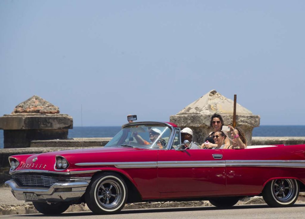 Turistas pasean en un auto clásico por el Malecón de La Habana. Foto: Yander Zamora / EFE.