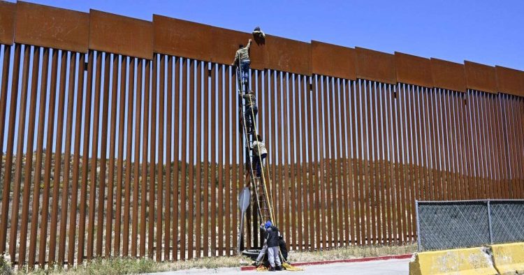 Varios inmigrantes indocumentados intentan saltar la cerca fronteriza con Estados Unidos. Foto: Denis Poroy / AP.