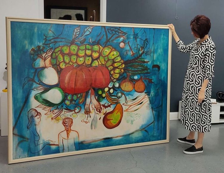 Mujer muestra una obra de Rodríguez, que pertenece a la serie “Frutas y realidad”. Foto: perfil en Facebook de la Fundación Mariano Rodríguez.
