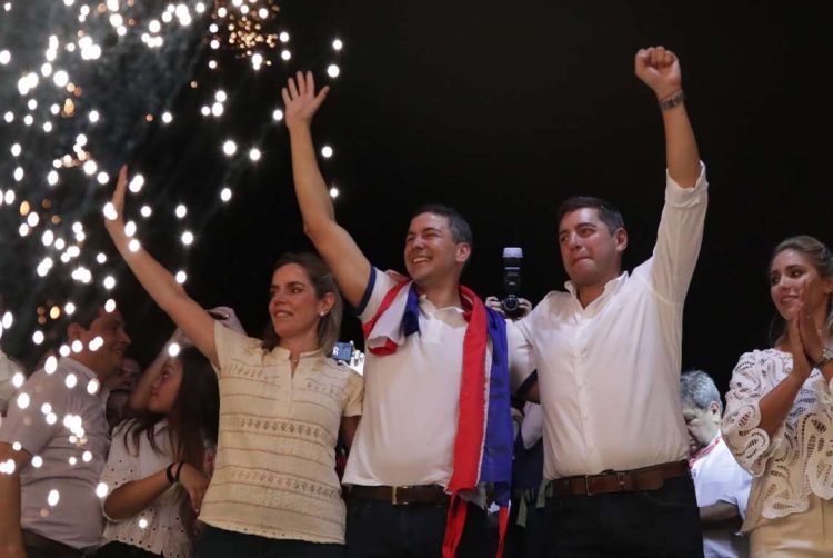 El presidente electo de Paraguay, Santiago Peña (centro), celebra junto a su esposa Leticia Ocampos y el vicepresidente electo (der.), Pedro Alliana, tras su victoria en las elecciones de este domingo. Foto: Raúl Martínez / EFE.