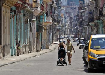 Una mujer camina con un coche para niño por una calle de la Habana.  Foto: Ernesto Mastrascusa/EFE.