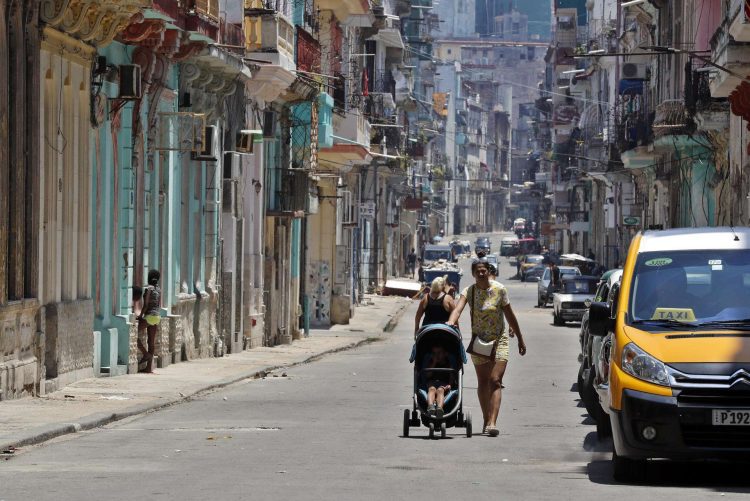 Una mujer camina con un coche para niño por una calle de la Habana.  Foto: Ernesto Mastrascusa/EFE.