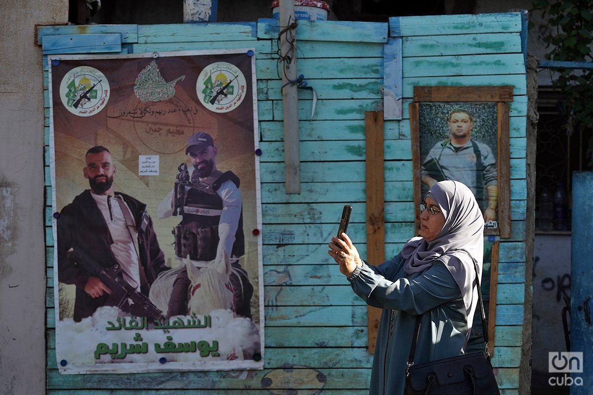 Una mujer toma fotos del campamento. Al fondo, fotos de milicianos muertos en combate y considerados mártires por los palestinos. Foto: Alejandro Ernesto.