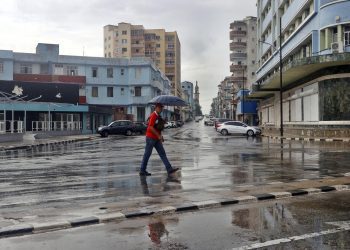 Un hombre se protege de la lluvia, en La Habana. Foto: Ernesto Mastrascusa/EFE.