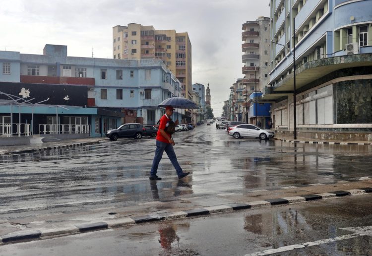 Un hombre se protege de la lluvia, en La Habana. Foto: Ernesto Mastrascusa/EFE.