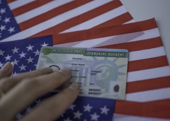 Permanent Resident Green card  of United states of America on flag of USA. Foto: www.telemundo.com