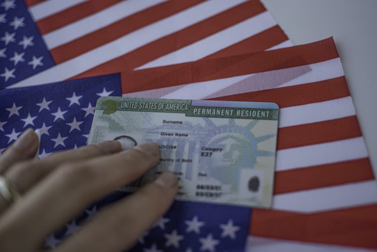 Permanent Resident Green card  of United states of America on flag of USA. Foto: www.telemundo.com