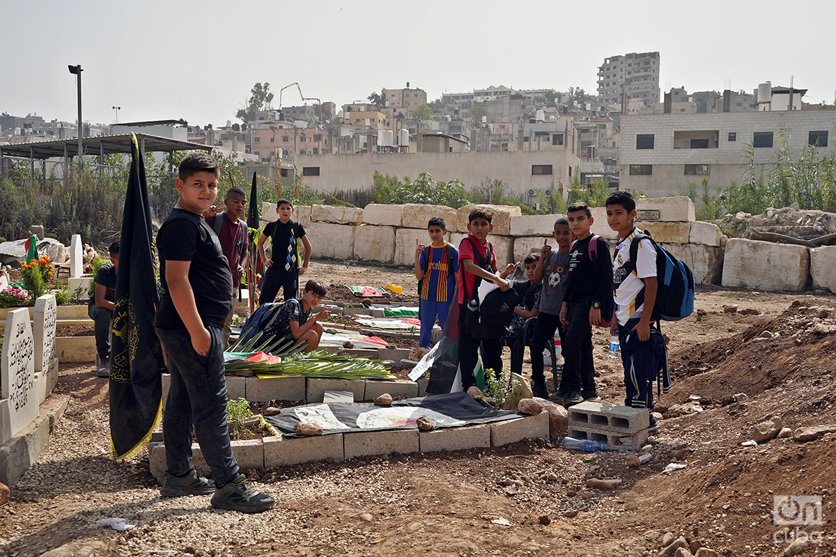 Un grupo de niños posa en el cementerio del campo de refugiados palestinos de Nur Shams, en Cisjordania ocupada, junto a las tumbas de milicianos que murieron en los combates del 19 y 20 de octubre. Foto: Alejandro Ernesto.