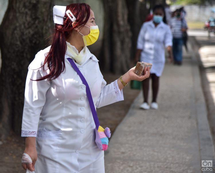 Una especialista de la salud con barbijo y unas barras de maní en la mano, en La Habana. Foto: Kaloian Santos Cabrera.