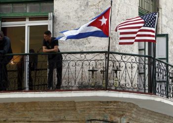 Cubanos conversan junto a banderas de Estados Unidos y Cuba, en La Habana. Foto: Ernesto Mastrascusa, tomada de El País.