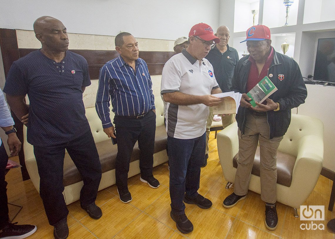 El Dr. Félix Julio Alfonso entrega dos libros a Tony Oliva en el Estadio Latinoamericano de La Habana. A su lado, expeloteros cubanos. Foto: Otmaro Rodríguez. 