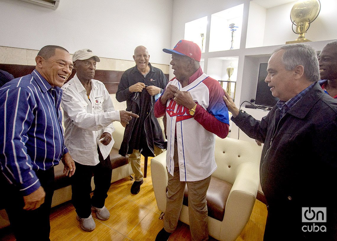 Tony Oliva se prueba la camiseta del equipo Cuba de béisbol, junto a autoridades deportivas y expeloteros cubanos, en el Estadio Latinoamericano de La Habana. Foto: Otmaro Rodríguez. 