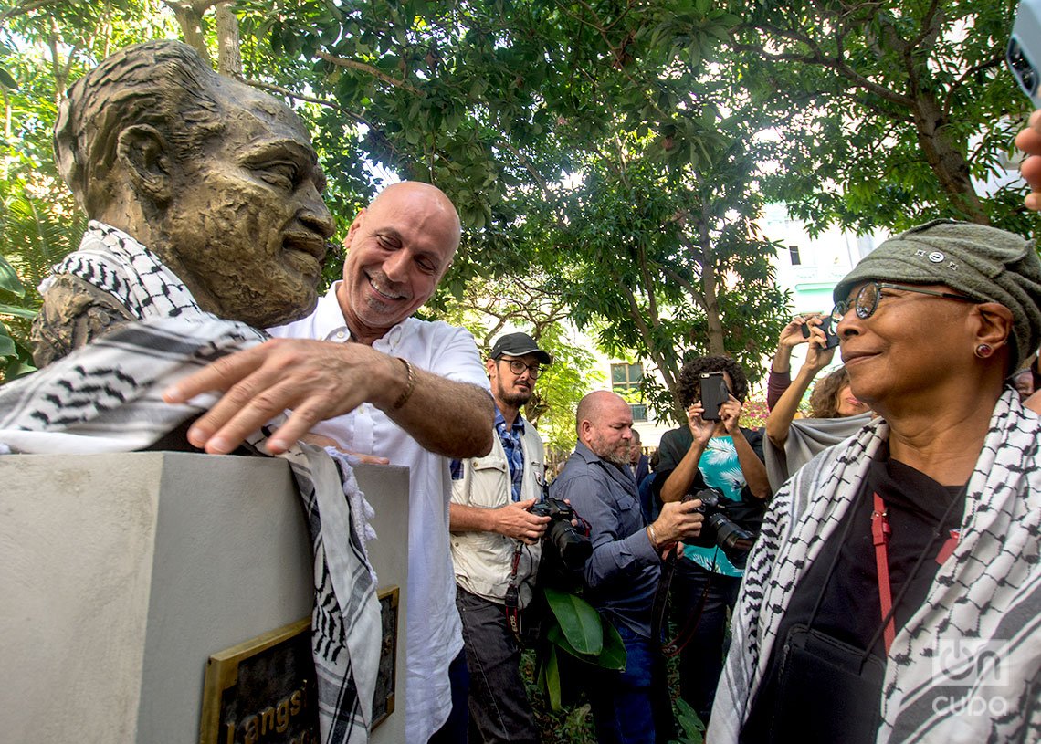 El artista y activista estadounidense Andy Shallal, coloca una kufiya palestina alrededor del cuello del busto de Langston Hughes en el Patio de la Poesía, en La Habana. Junto a él, la escritora Alice Walker. Foto: Otmaro Rodríguez.
