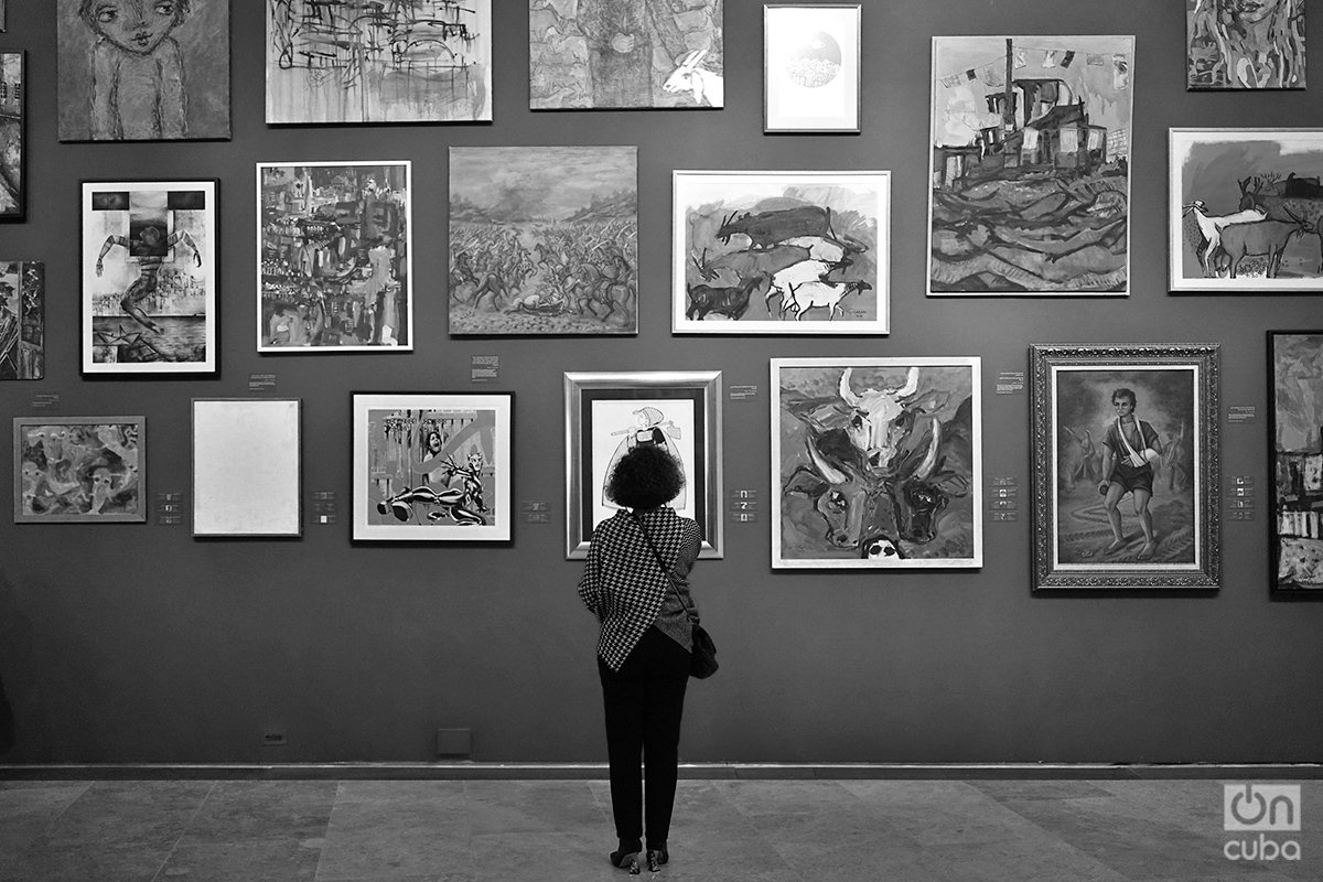 Una mujer observa las pinturas de artistas gazatíes que forman parte de la muestra "Esto no es una exposición". Foto: Alejandro Ernesto.