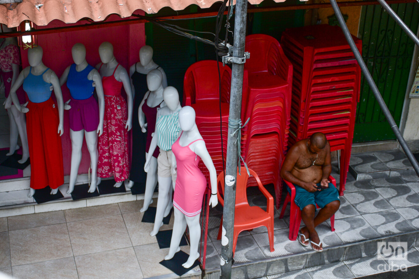  Un vecino está sentado al lado de uno de los comercios de ropa en Rocinha. Foto: Kaloian.

