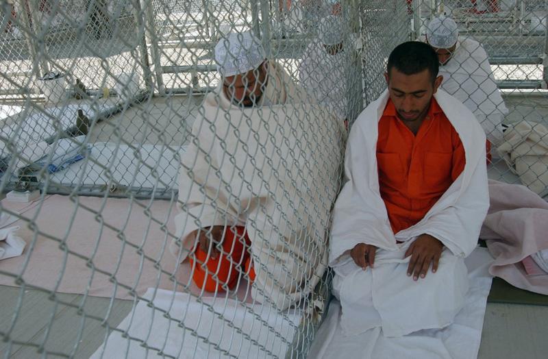 La cerca en el Camp X Ray permitía cierta cercanía entre los prisioneros que podían, como en la imagen, rezar juntos. Los detenidos dormían sobre alfombrillas y se cubrían con mantas muy delgadas. Foto: Shane T. McCoy / USMC.