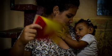 Una madre echa aire a su hija durante un apagón en Cuba. Foto: Otmaro Rodríguez / Archivo.