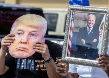 Un partidario de Joe Biden sostiene un retrato del presidente estadounidense (der) junto a un seguidor de Donald Trump que lleva una foto del exmandatario (izq) en Florida, Estados Unidos. Foto: Cristóbal Herrera-Ulashkevich / EFE.