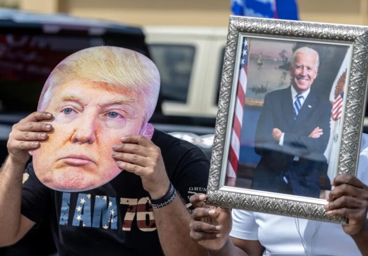 Un partidario de Joe Biden sostiene un retrato del presidente estadounidense (der) junto a un seguidor de Donald Trump que lleva una foto del exmandatario (izq) en Florida, Estados Unidos. Foto: Cristóbal Herrera-Ulashkevich / EFE.