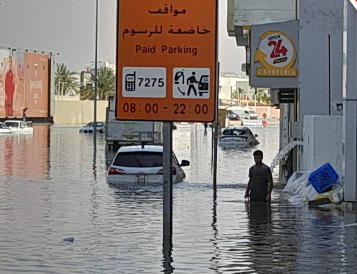 Un hombre y varios autos en una calle inundada en el barrio de Al Barsha luego de las torrenciales lluvias caídas en Dubái. Foto: OnCuba.