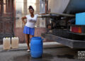 Una mujer intenta llenar un tanque de agua desde un camión cisterna (pipa) en Centro Habana, Cuba. Foto: Alejandro Ernesto / Archivo.