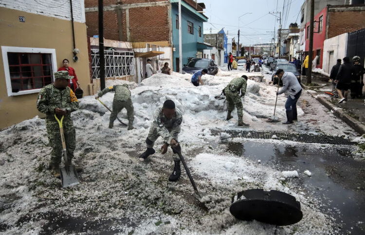 Soldados del Ejercito Mexicano retiran granizo de las calles en Puebla. Foto: Hilda Ríos/EFE.