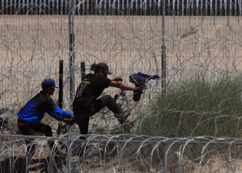 Migrantes ilegales intentan cruzar por una barricada de alambre con púas en las inmediaciones de la frontera con Estados Unidos y México. Foto: Luis Torres / EFE.