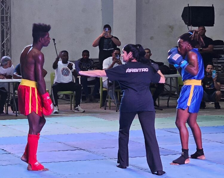 Combate en la modalidad de Sanda, entre el joven trans Ely Malik, de azul, y su rival, en el estadio Martí, en La Habana. Foto: Perfil de Facebook de Claudio Peláez Sordo.