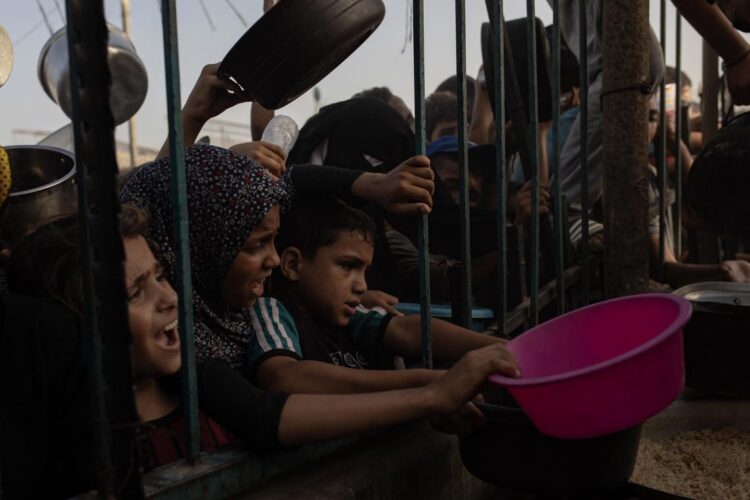 Niños palestinos desplazados por la guerra intentan recoger alimentos donados por un grupo caritativo, en el campamento de Khan Yunis, en el sur de la Franja de Gaza, el 15 de junio de 2024. Foto: Haitham Imad / EFE.