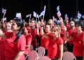 Asistentes al acto por el 26 de julio en Sancti Spíritus levantan banderas cubanas. Foto: @PresidenciaCuba / X.