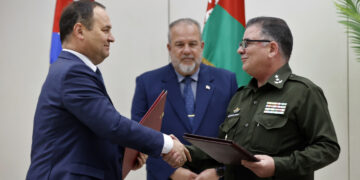 El primer ministro de Bielorrusia, Román Golovchenko (i), firma un acuerdo junto al Ministro del Interior cubano el General de Brigada Lázaro Alberto Álvarez Casas, en presencia del primer ministro cubano Manuel Marrero, en La Habana, el 16 de julio de 2024. Foto: Ernesto Mastrascusa / EFE.