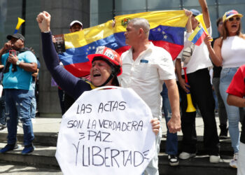 Una mujer sostiene un cartel durante una protesta contra los resultados oficiales de las elecciones en Venezuela, dados por el CNE, en Caracas. Foto: Ronald Peña R. / EFE.