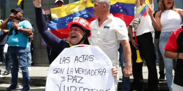 Una mujer sostiene un cartel durante una protesta contra los resultados oficiales de las elecciones en Venezuela, dados por el CNE, en Caracas. Foto: Ronald Peña R. / EFE.