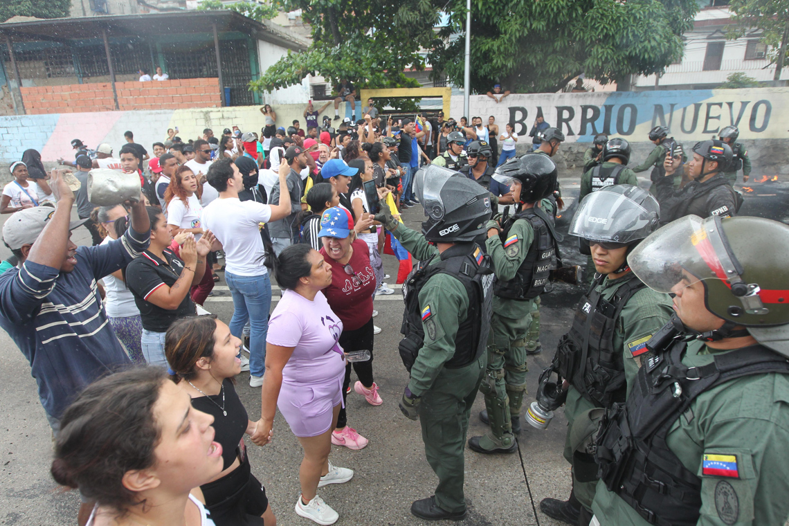 Personas reclaman frente a integrantes de la Guardia Nacional Bolivariana (GNB) durante una protesta por los resultados oficiales de las elecciones presidenciales, en el sector del Primero de Mayo en Caracas, el 29 de julio de 2024. Foto: Manuel Díaz / EFE.